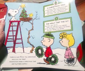 Book spread featuring Snoopy putting star on a tree while Woodstock looks on and Charlie Brown and Sally walk by, with the lyrics for two songs