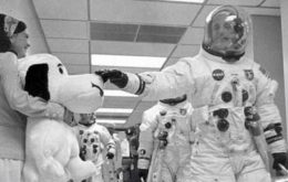 An astronaut touches a stuffed Snoopy