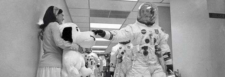 An astronaut touches a stuffed Snoopy